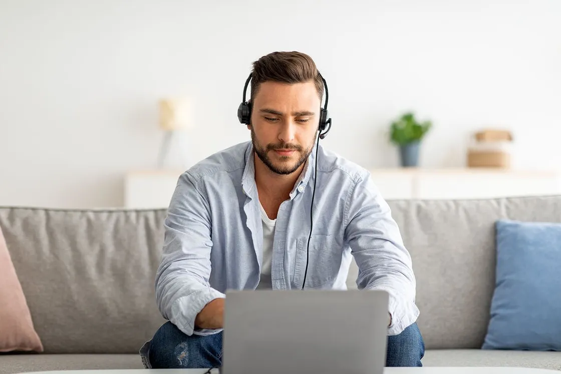 Agente con audífonos trabajando desde su casa en un notebook