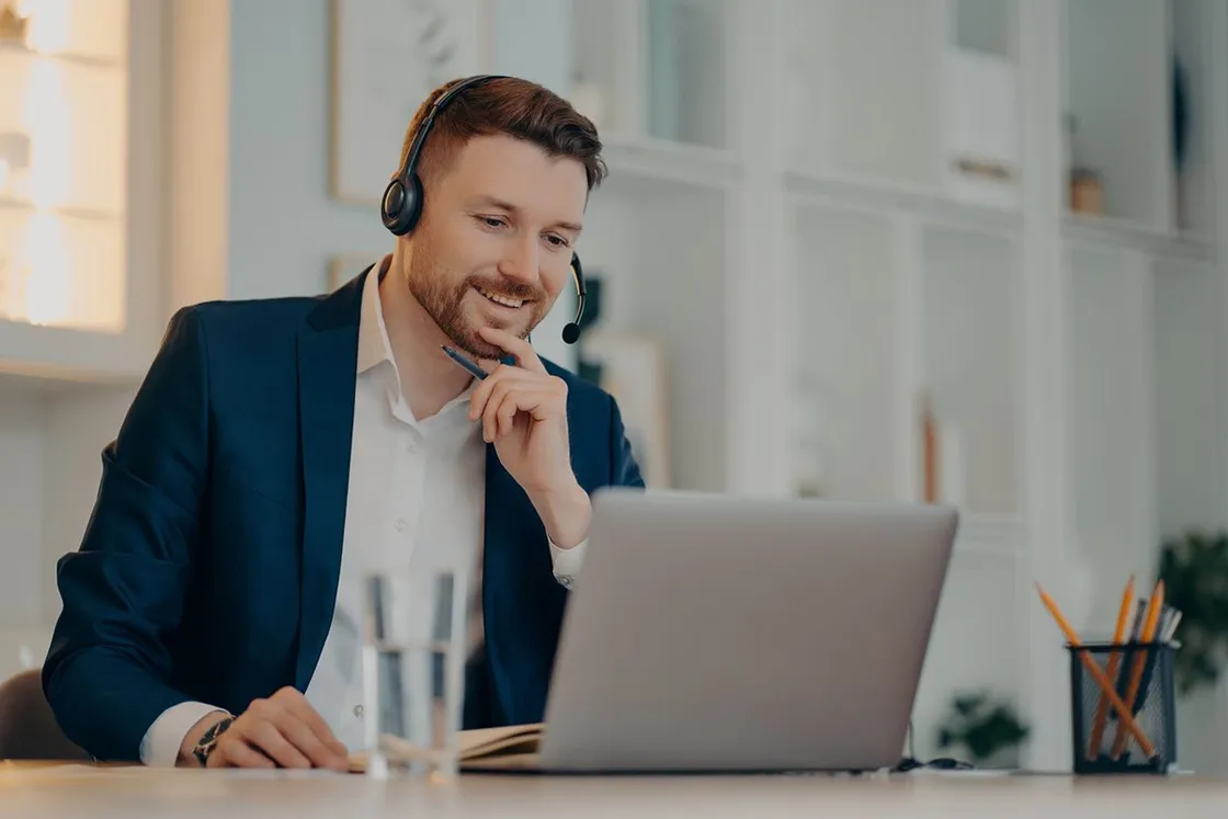 Ejecutivo con audífonos sonriendo frente a su computador